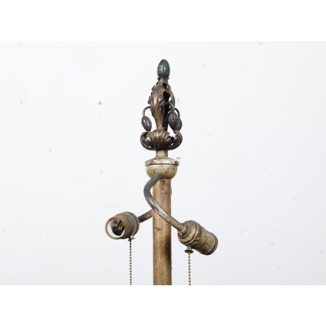 A French steel and brass floor lamp from circa 1930 with two light sockets, scrolling legs and foliage motifs. This French...