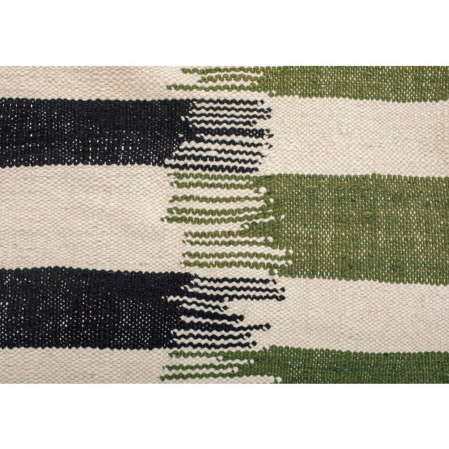 Bold handwoven wool rug featuring a dynamic gradient of Midnight Black, Ivory, and Olive Green. Its sharp, modern design...