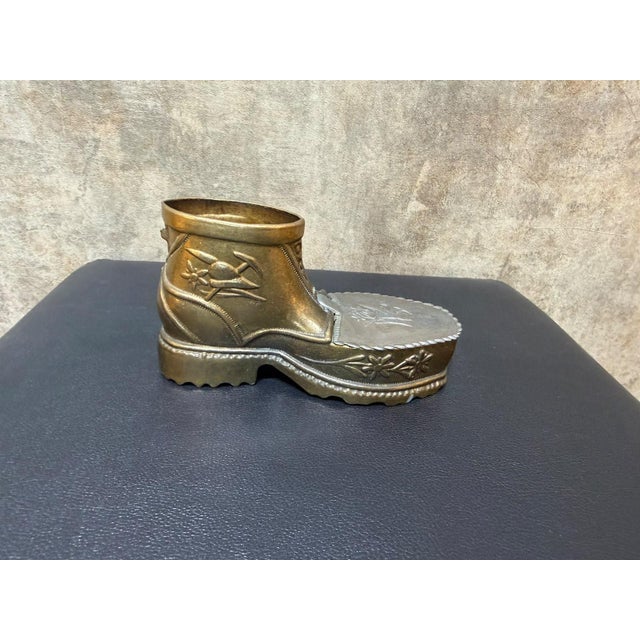 A miniature lace-up mountain boot with a lugged sole, fitted with a hinged lid over the toe that opens onto a shallow...