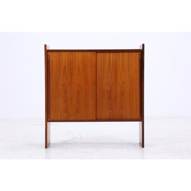 Beautiful vintage teak chest of drawers with sliding doors from the 1960s, featuring a clean, compact design and a calm,...