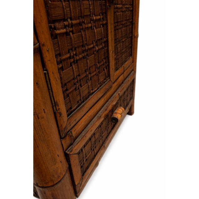 A beautifully aged 1970s bamboo cabinet featuring woven rattan inset panels and a richly saturated honey-amber finish with...