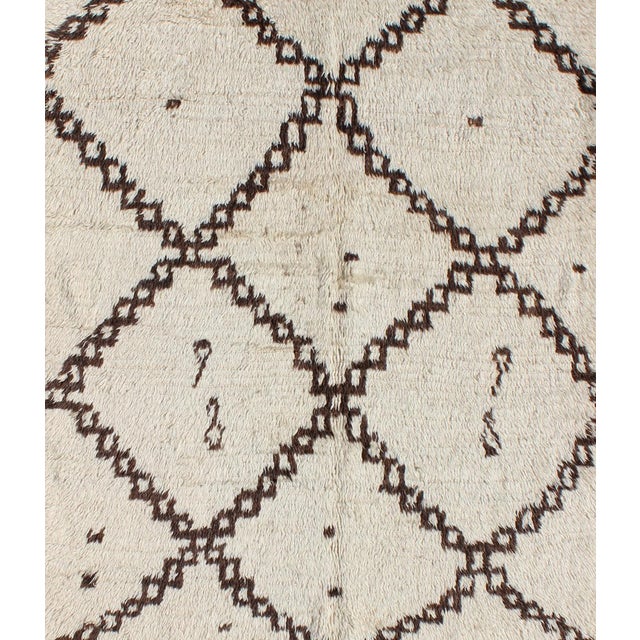 Measures: 4'10'' x 7'0''. This graphic handwoven, tribal Beni Ourain rug features an all-over design of large,...