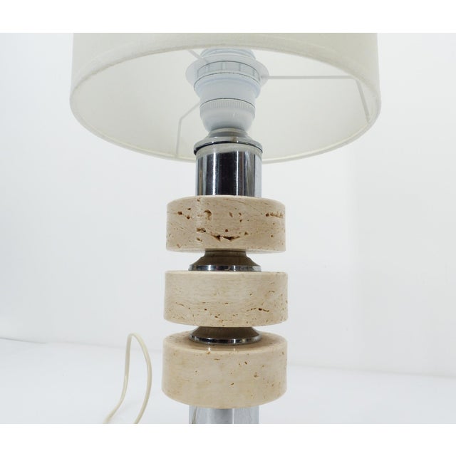 Architectural table lamp composed of stacked travertine discs separated by cylindrical chrome-plated metal elements. A...