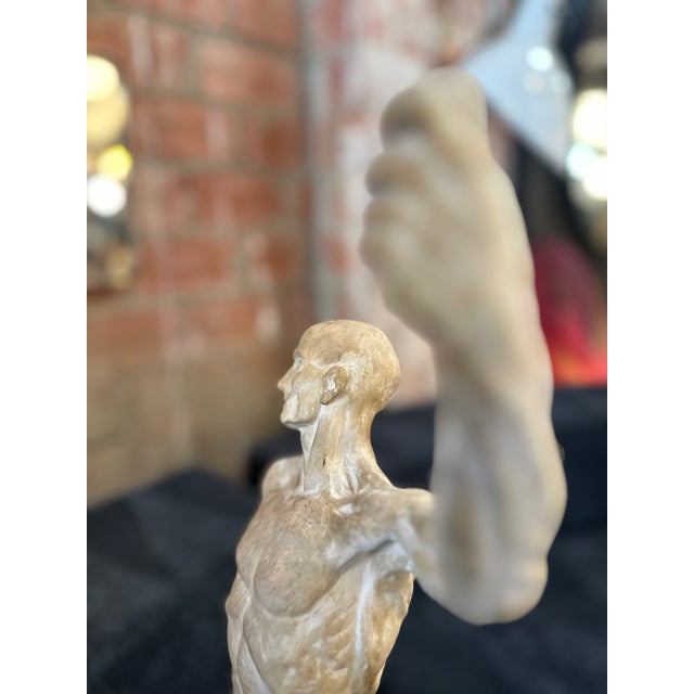 The figure’s head is slightly tilted, giving it an expressive look, and the torso is sculpted to reveal muscles and...