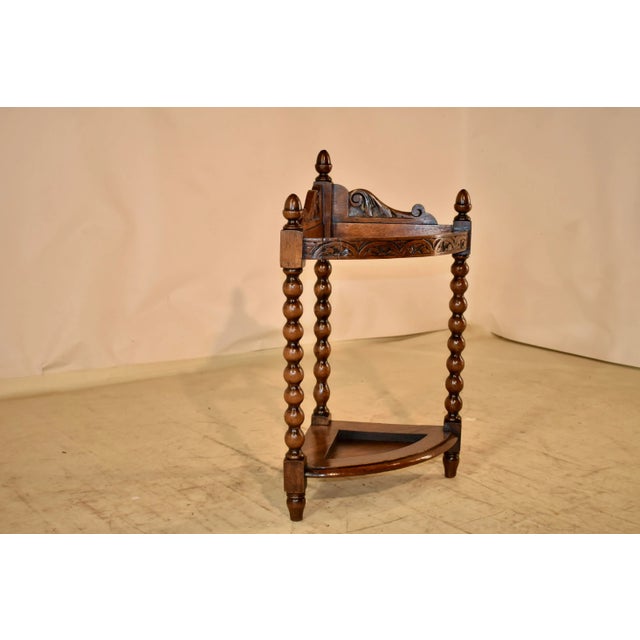 19th century oak corner walking stick stand from England. The top has a scalloped and hand carved decorated back,...