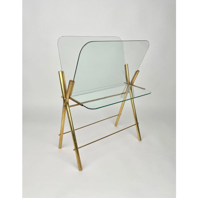 Magazine rack stand in a brass and glass structure which can also be used as a table as it features a glass shelf. Made in...