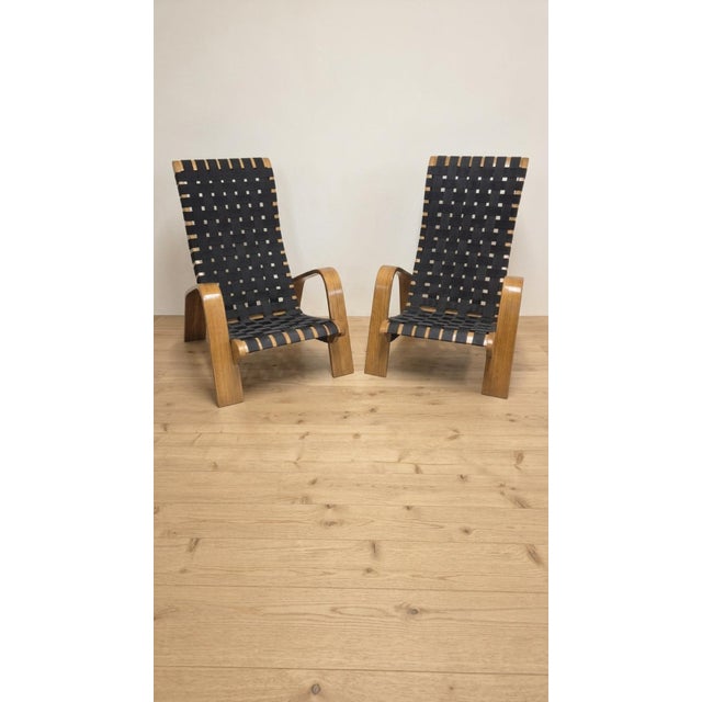 A distinctive mid-century armchairs from Czechoslovakia, featuring a sculptural wooden frame, curved armrests, and a woven...