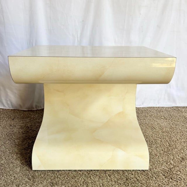 These sculptural postmodern side tables feature a bold wave-like silhouette finished in a creamy faux goatskin laminate....