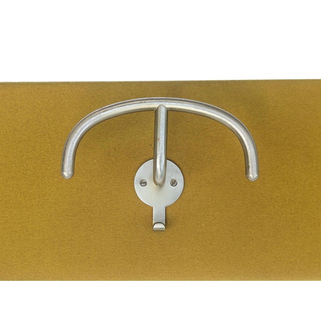 Coat rack made in Italy in the 1960s. Wooden structure upholstered in mustard-colored fabric. Features three nickel-plated...