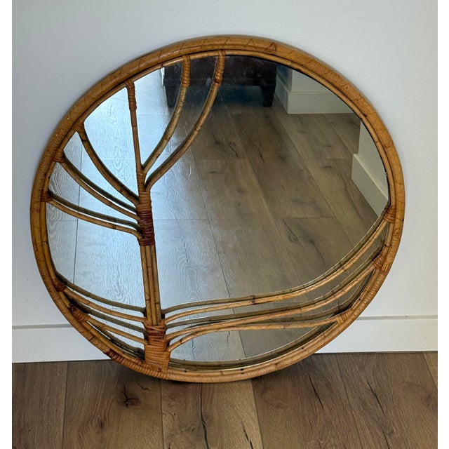 A large mid-century round rattan wall mirror, with a bent-bamboo frame worked into a pine needle type motif and bound with...