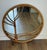 A large mid-century round rattan wall mirror, with a bent-bamboo frame worked into a pine needle type motif and bound with...