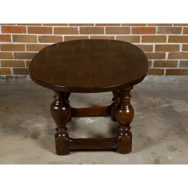 An English Georgian period pine table from the 18th century with oval top, turned legs and side stretchers. This exquisite...