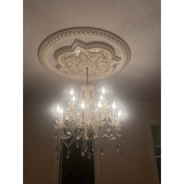 Large vintage crystal chandelier featuring elegant glass arms, faceted crystal prisms, and French Empire/Hollywood Regency...