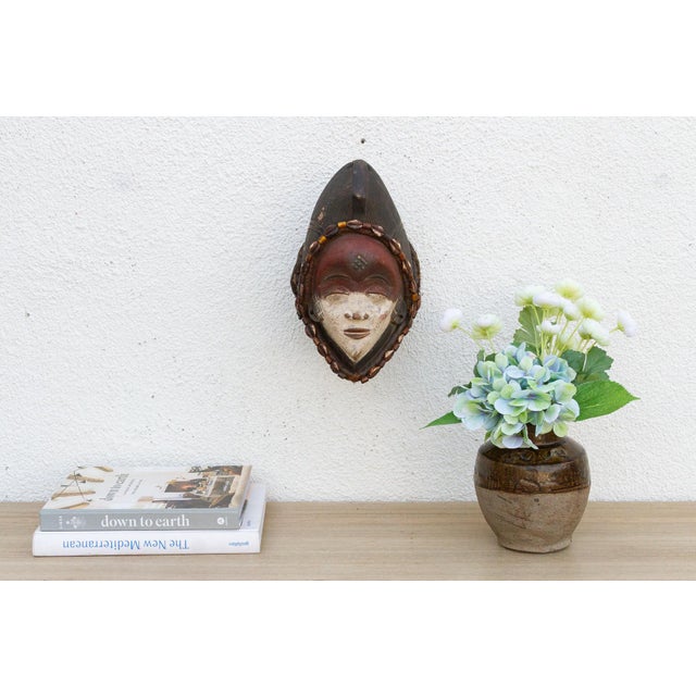 Discover the captivating allure of authentic African art with this vintage hand-carved wooden mask. Imbued with a rich...