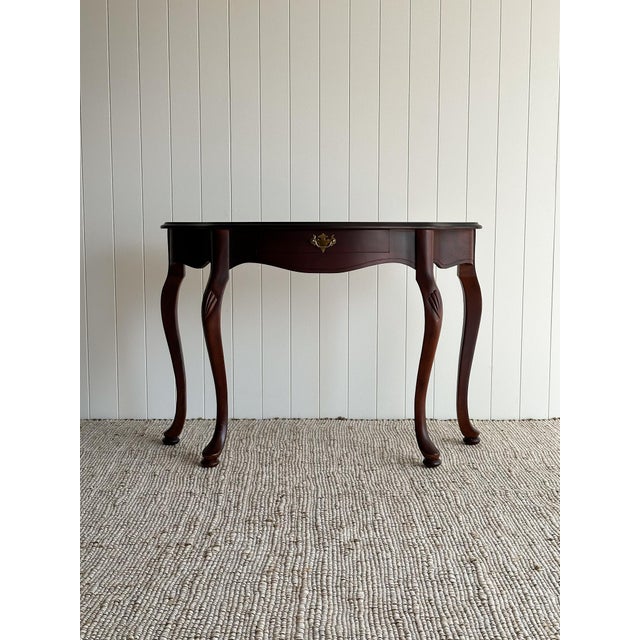This vintage mahogany demi-lune entryway table features a graceful serpentine front, long cabriole legs, and carved shell...
