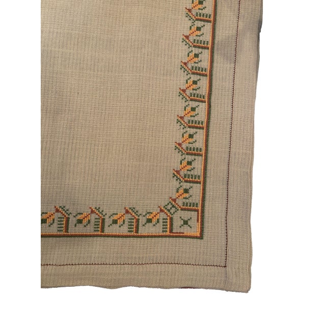 Large vintage linen tablecloth featuring a hand-embroidered border. It is decorated with repeating geometric folk motifs...