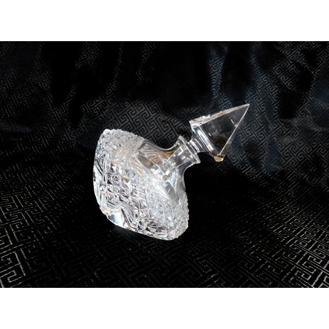 This is a cut glass top shaped (wide middle, small base) perfume bottle with a pyramid shaped stoper that may not...