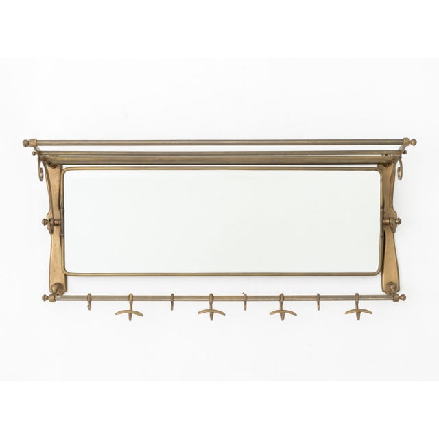 Art Deco Style Brass Mirrored Coat Rack, with articulated beveled glass mirror plate and eight hooks. 17" H x 39.5" W x...