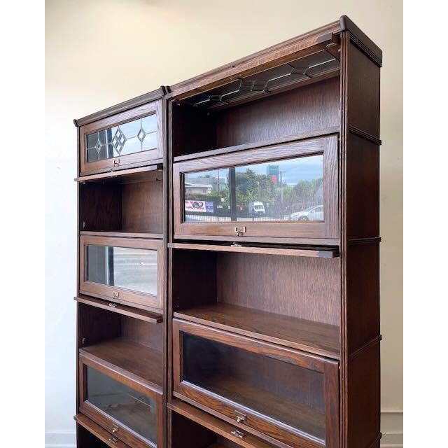 Pair of vintage oak barrister-style display bookcases featuring beautiful leaded glass accents, sliding glass doors, and...