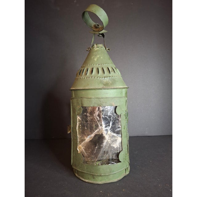 Offered is an exceptional, authentic early 19th-century American punched tin lantern featuring a rare, intact front mica...