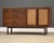 A mid century modern walnut sideboard credenza made by Founders with three drawers and two cane doors. Professionally...