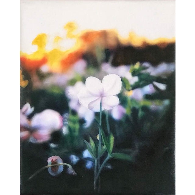 This oil on canvas artwork captures a delicate white flower standing out amidst a blurred, vibrant background of blooming...