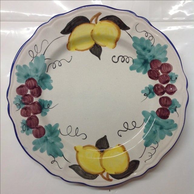 Grapes and lemons are hand-painted onto the border of this Italian wall charger. Colors include royal blue, turquoise,...
