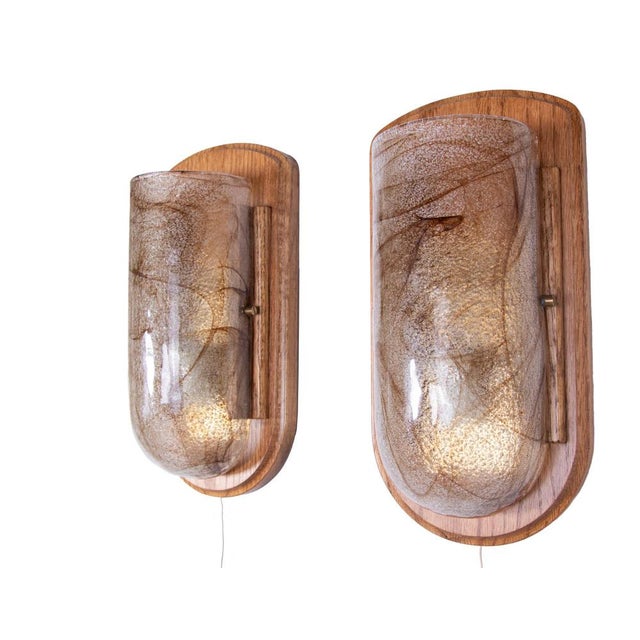 Elegant pair of modernist wall sconces with handblown amber Murano glass with on a wooden wall mount. Manufactured in...