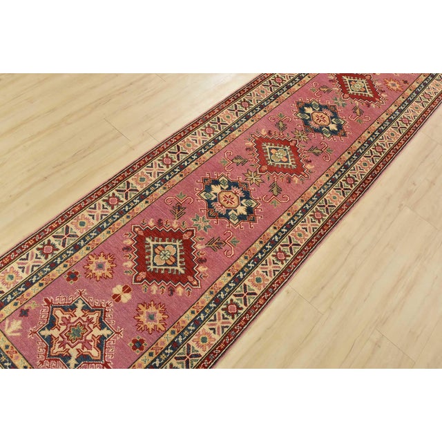A tribal Caucasian Kazak runner hand-knotted with fine wool on a cotton foundation. This rug features a row of geometric...