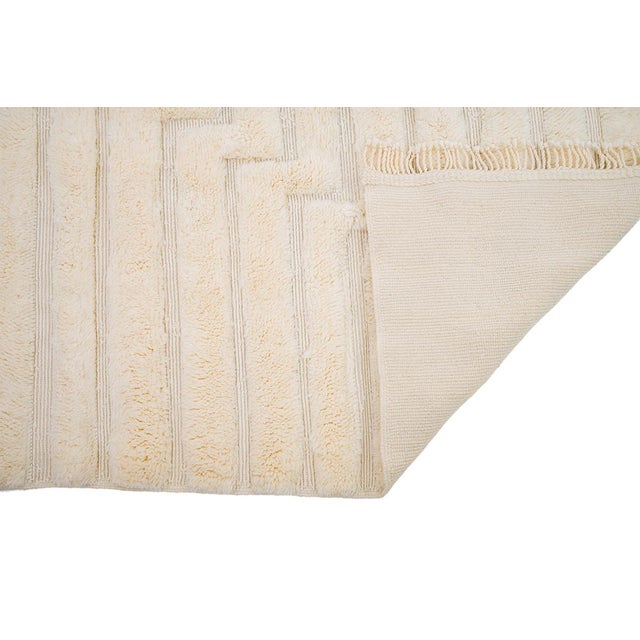 Pure tone, pure texture — sculpted from a single shade of ivory. This hand-knotted Moroccan wool rug relies entirely on...