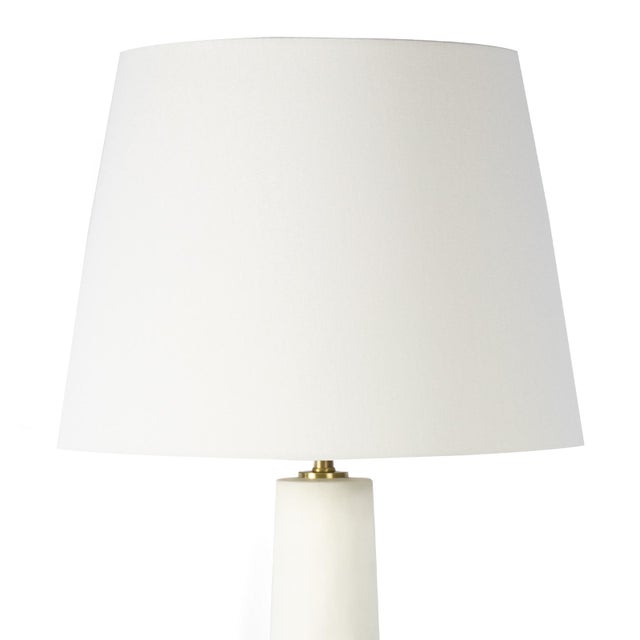 Cast a warm glow on your living room or bedroom with the Kayla Ceramic Table Lamp. This unique piece features a white...