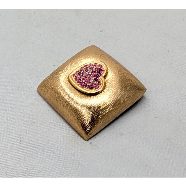 Late 1950s or 1960s rectangular slightly asymmetrical goldtone Florentine finish pavé round faux-rubies forming a heart...