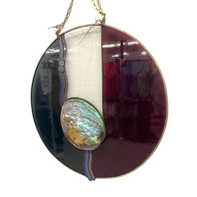 Decorative round stained glass panel featuring a dimensional abalone shell centerpiece. The circular composition is...