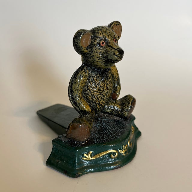 Worn doorstop, perfect for a child's room. Teddy Bear sitting on a decorative green stoop.