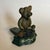Worn doorstop, perfect for a child's room. Teddy Bear sitting on a decorative green stoop.