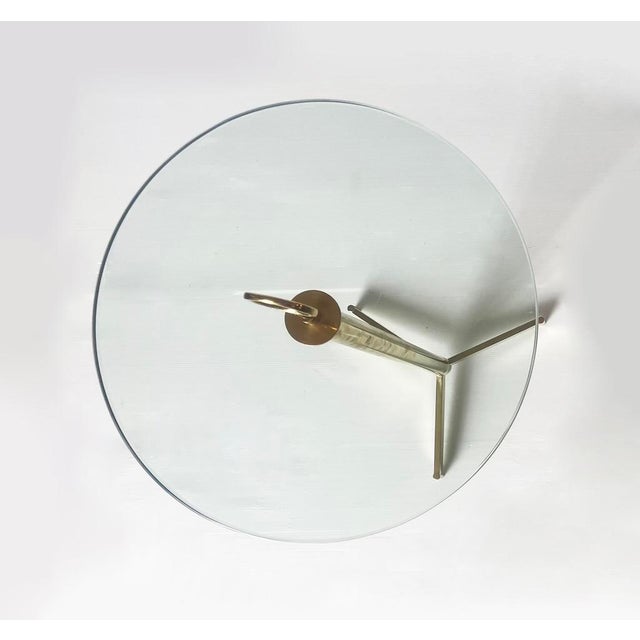 Elegant vintage coffee table with a brass frame and glass top. A distinctive brass ring handle above the top is both...