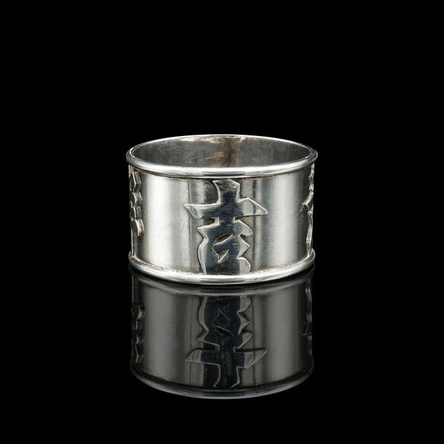 This is an antique personalised napkin ring. A Chinese, silver decorative holder, dating to the late Victorian period,...
