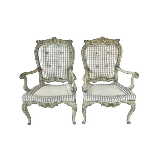 A Pair of 18th Century Italian Rococo Armchairs. Each chair is carved and polychrome painted in soft greens, pinks, and...