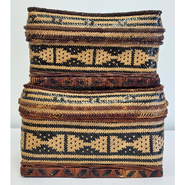 Vintage pair of woven reed baskets in natural tone with black patternwork throughout. Largest measures 9"W X 5"D X 6"H and...