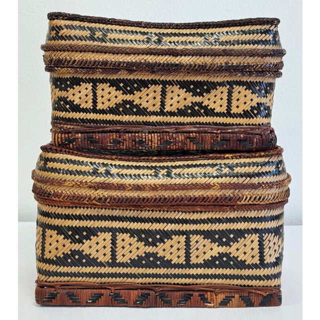 Vintage pair of woven reed baskets in natural tone with black patternwork throughout. Minor age wear throughout,...