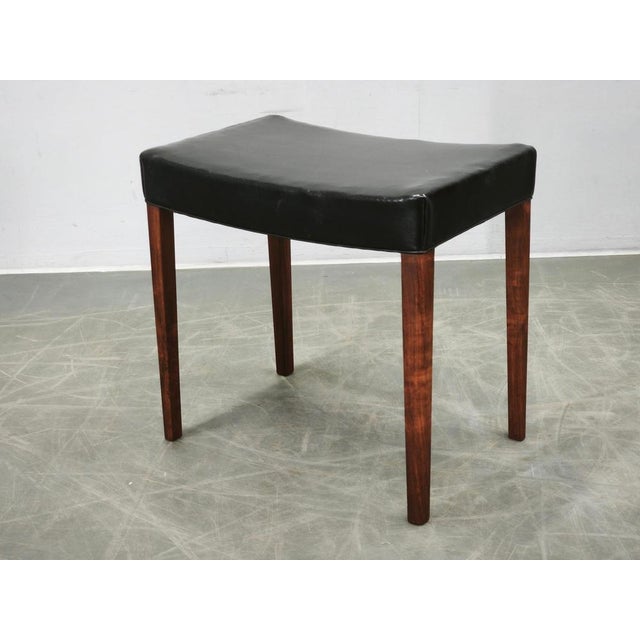 Elegant Danish Modern stool from the 1960s, crafted in Denmark from wood and black leather. The stool embodies the...
