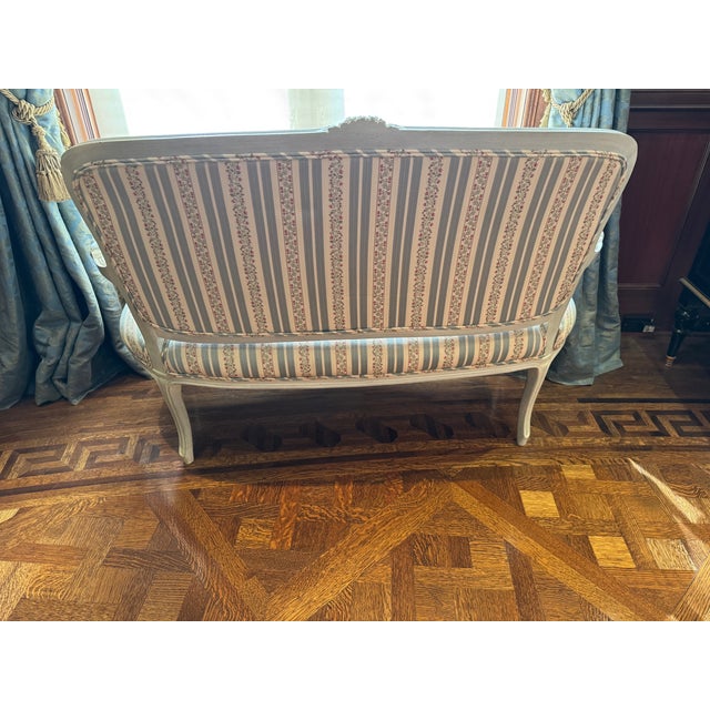 A graceful Louis XV–style settee featuring a beautifully carved and painted wood frame with classic cabriole legs and...