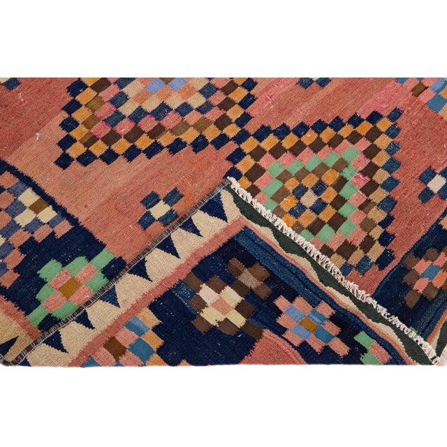 Beautiful vintage Turkish Kilim hand-knotted wool rug with a peach field. This piece has a navy blue frame and multicolor...