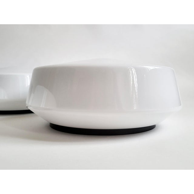 A minimalist white opaline glass flush mount ceiling or wall light, Austria, 1960s–1970s. The shallow domed glass shade is...