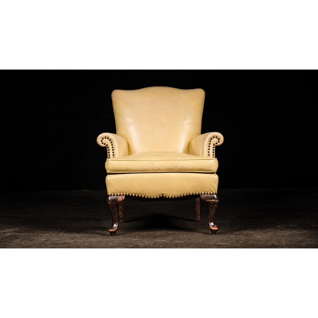 This unique vintage leather armchair features a bright canary yellow hue and bronze accent tacks.