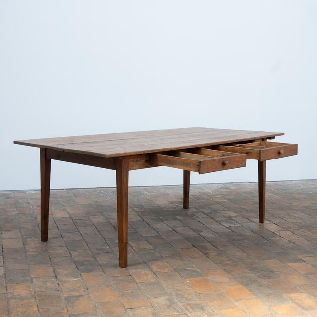 Solid fir farmhouse table, mounted on a two-legged base connected by a central stretcher. Two drawers in the front....