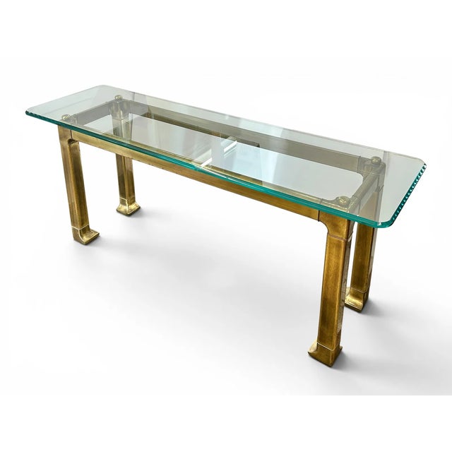 The unsigned table has a beveled glass top and a brass base. It has an Asian style, bracket corners with capped post tops,...