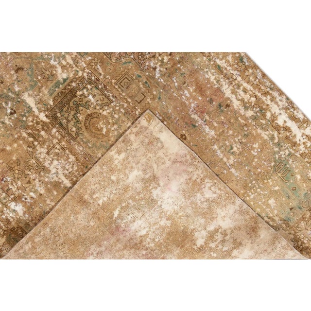 Beautiful hand-knotted vintage wool rug with a tan field. This distressed rug has red and blue accents featuring an all-...