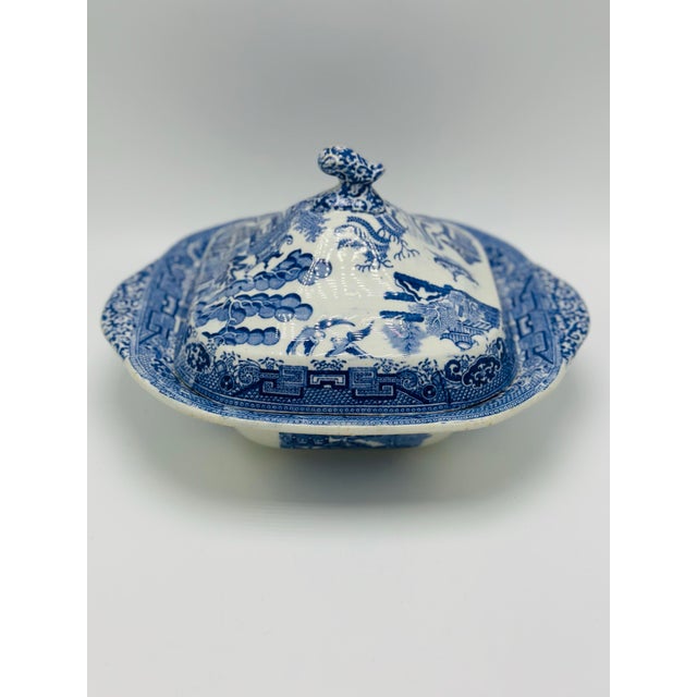 This charming antique blue and white transferware covered dish features the beloved Willow pattern, one of the most...