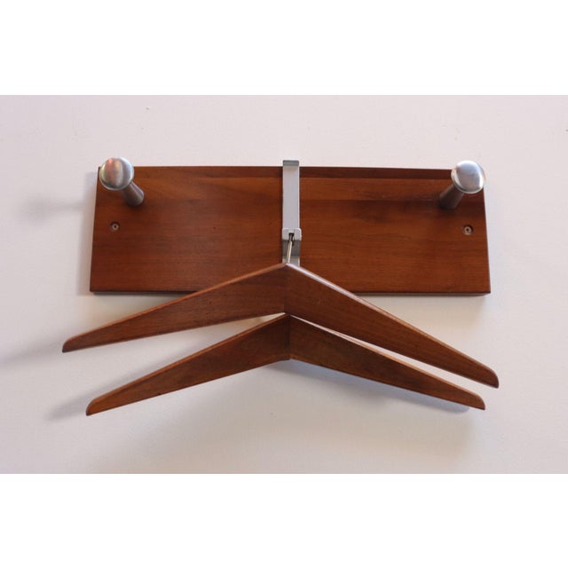 Modernist coat rack featuring a walnut mount with two anodized aluminum 'hooks' and dual bracket in which the two hangers...